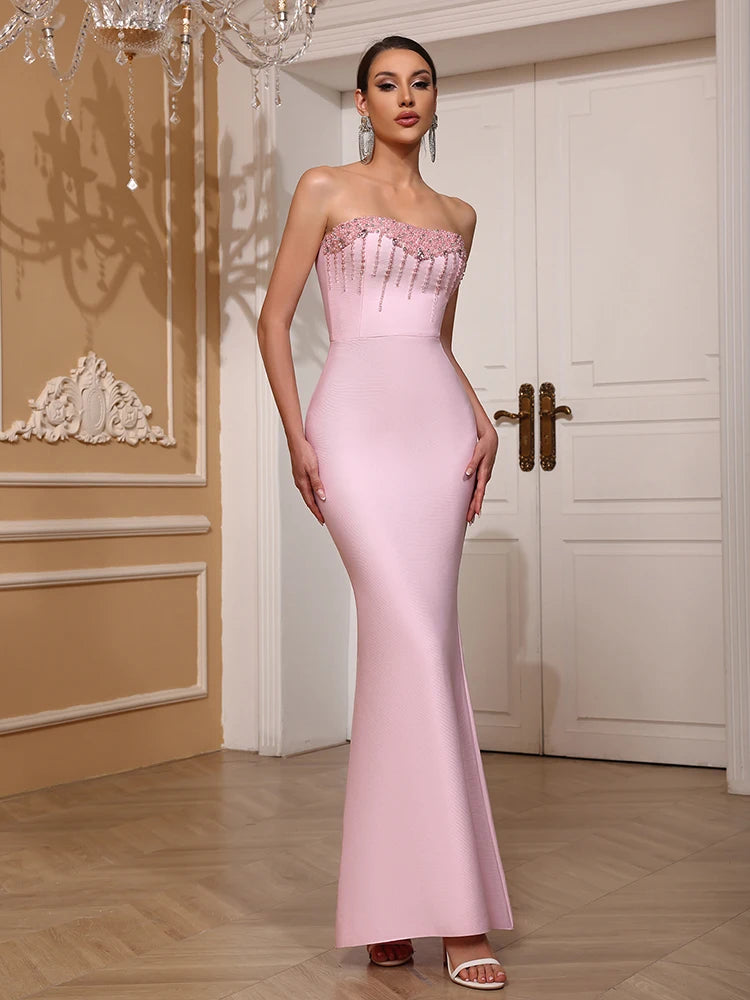 Woman in a pink strapless gown standing in an elegant room with decorative elements.