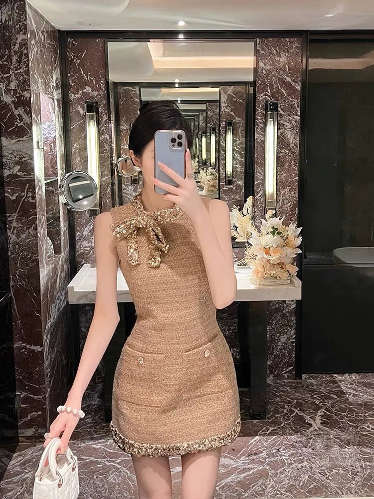 Person taking a mirror selfie wearing a brown dress with decorative elements in a marble bathroom.