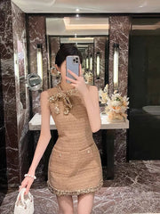 Person taking a mirror selfie wearing a brown dress with decorative elements in a marble bathroom.