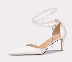 White high-heeled shoe with chain detail on a light gray background