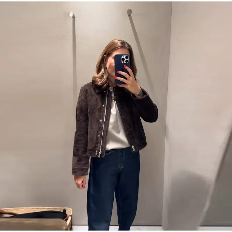 Person taking a mirror selfie wearing a brown jacket and blue pants.