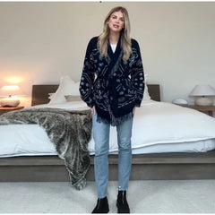 Woman wearing a dark blue patterned cardigan in a bedroom setting