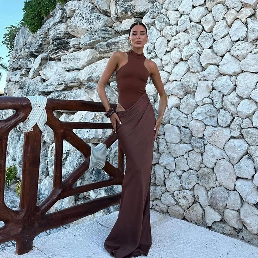 Woman in a brown dress standing against a stone wall