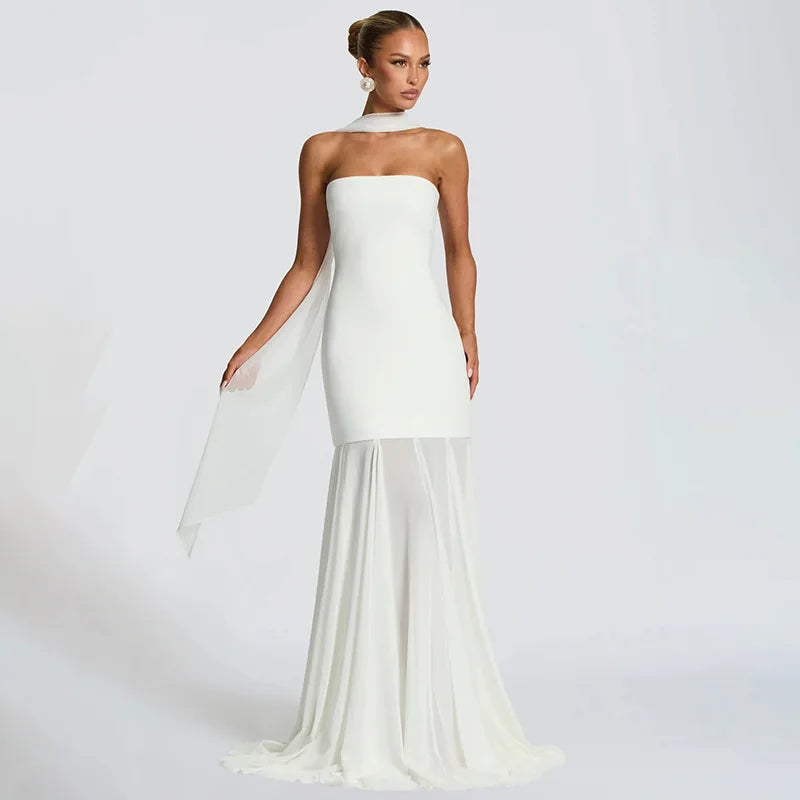 Woman wearing a strapless white gown with a sheer overlay on a plain background