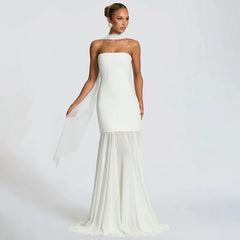 Woman wearing a strapless white gown with a sheer overlay on a plain background