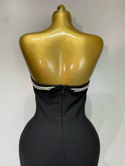 Black strapless dress with pearl detailing on a gold mannequin against a white background