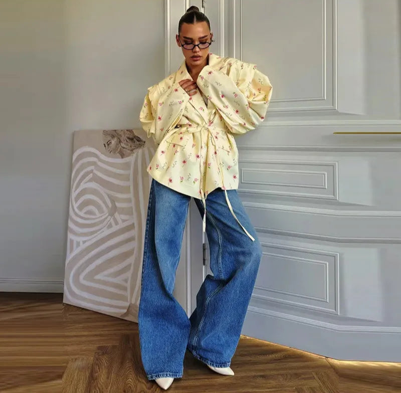 Person wearing a light-colored floral blouse and blue jeans in an indoor setting.