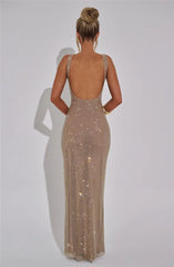 Woman wearing a sparkly, floor-length dress with a plain background
