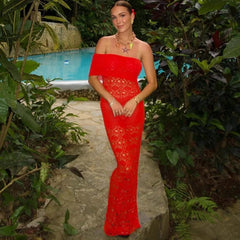 Woman in a red dress standing by a pool with greenery around