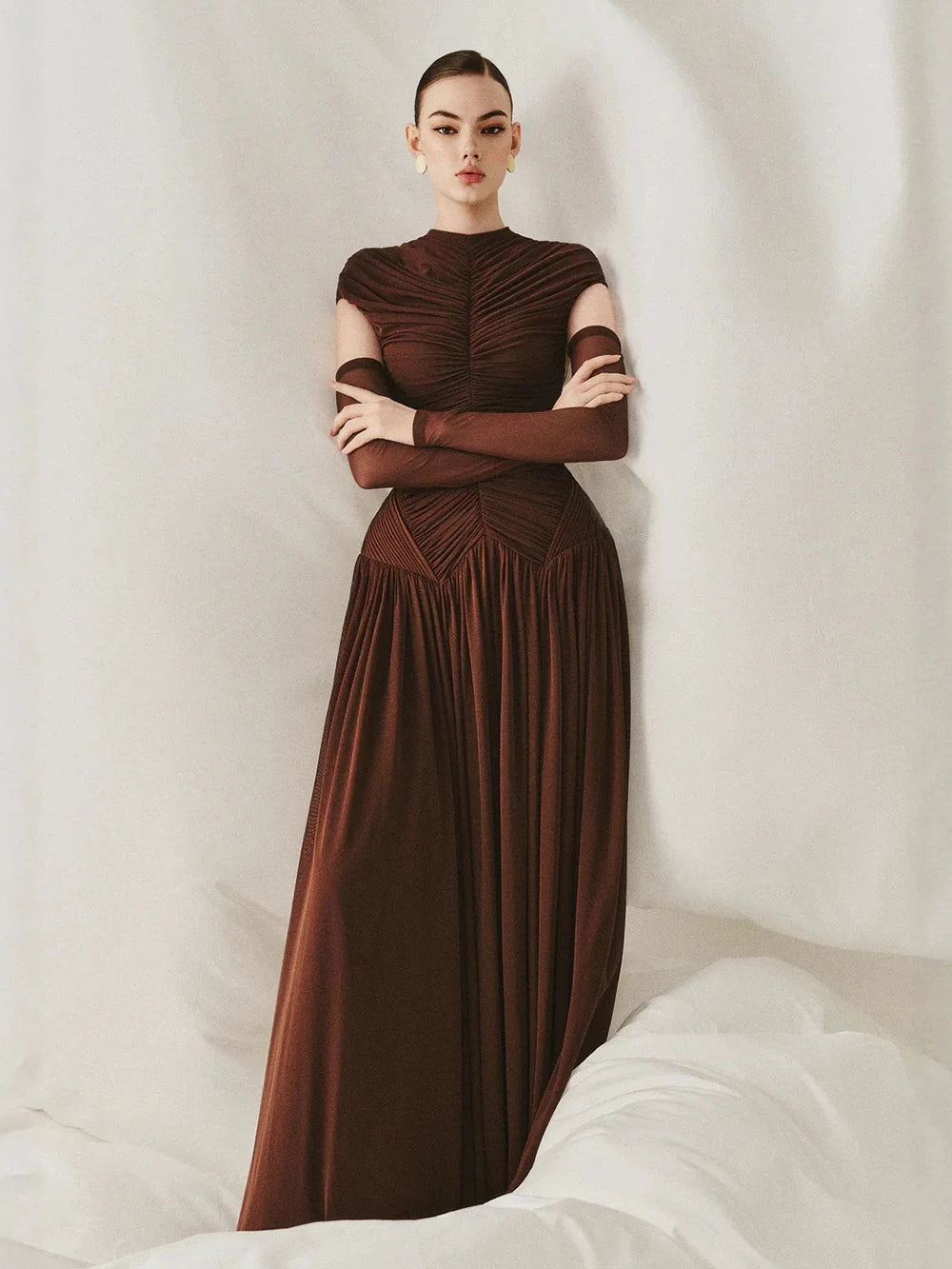 Model posing in a brown ruched mock neck maxi dress
