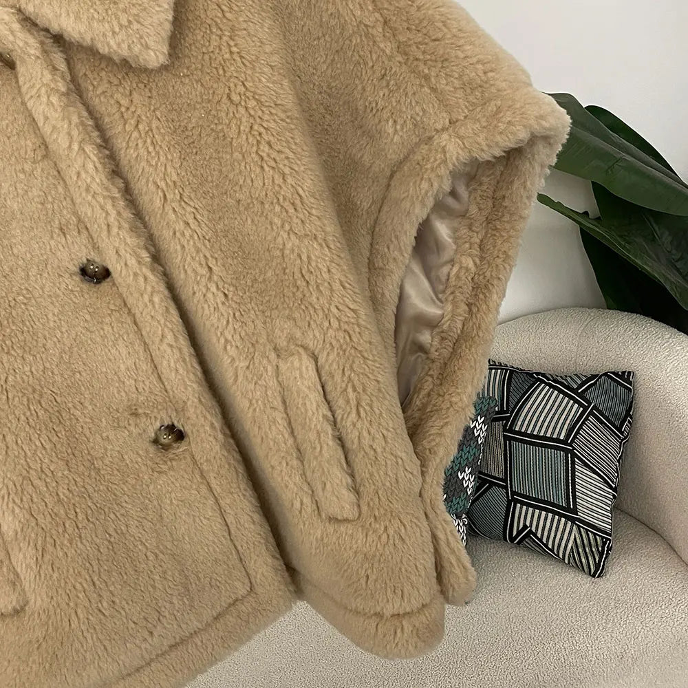 Beige sherpa coat draped over a chair with a decorative pillow in the background