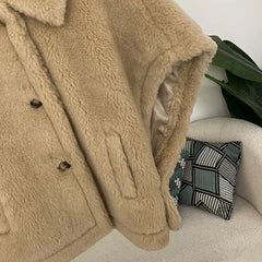 Beige sherpa coat draped over a chair with a decorative pillow in the background