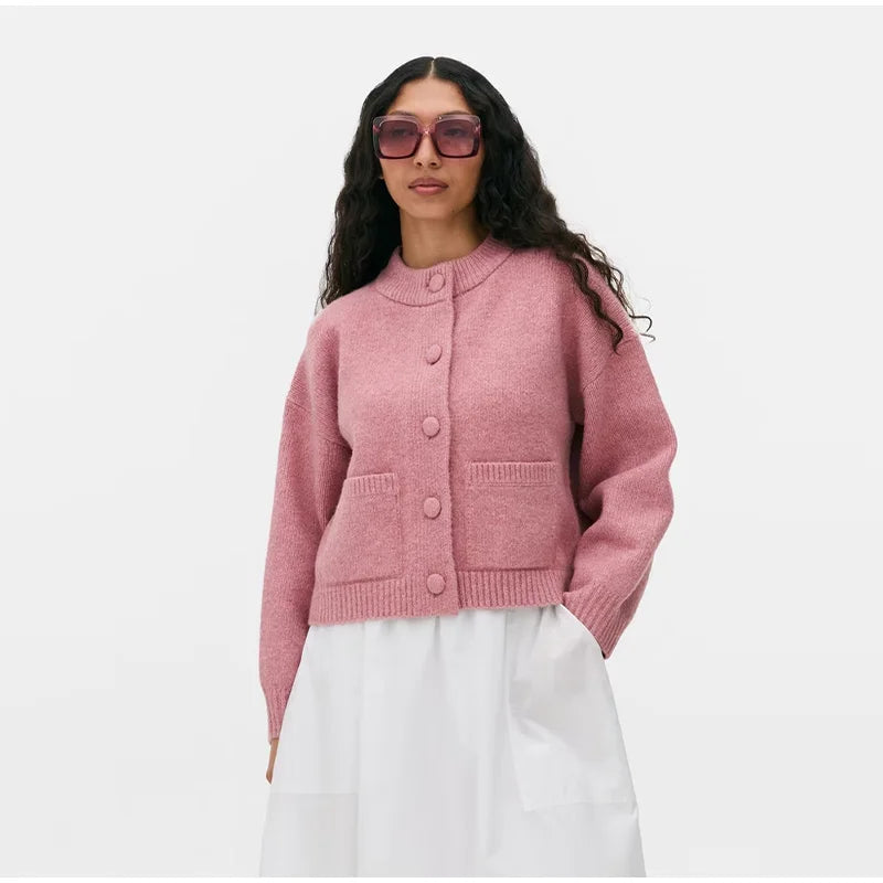 Woman wearing a pink cardigan and white pants on a white background