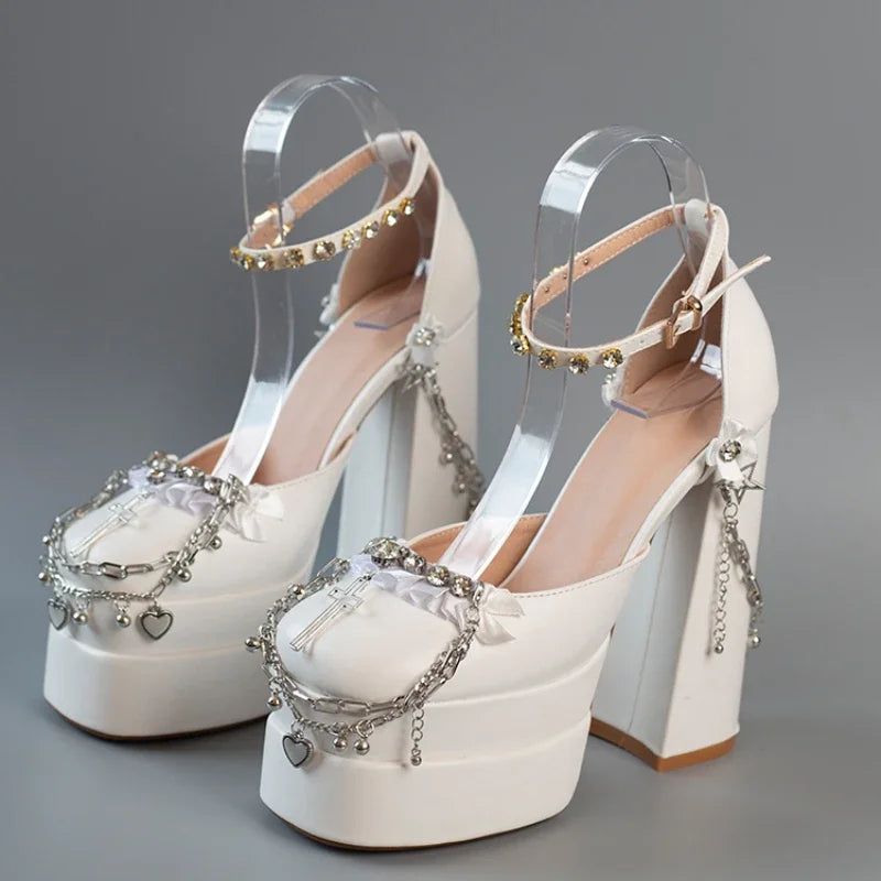 White high-heeled shoes with decorative straps and charms on a gray background