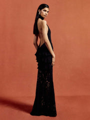 Woman wearing a black evening gown with a deep neckline and ruffled details on a red background