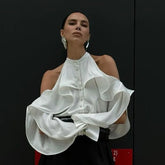 Woman wearing a white ruffled blouse against a black background