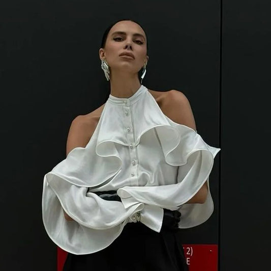 Woman wearing a white ruffled blouse against a black background