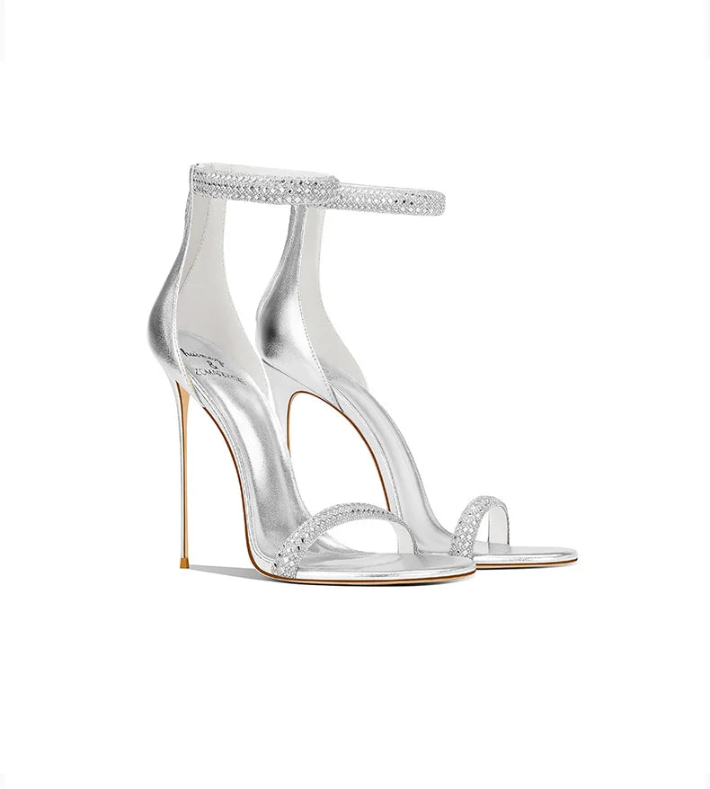 Clear high-heeled sandals with embellishments on a white background