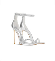 Clear high-heeled sandals with embellishments on a white background