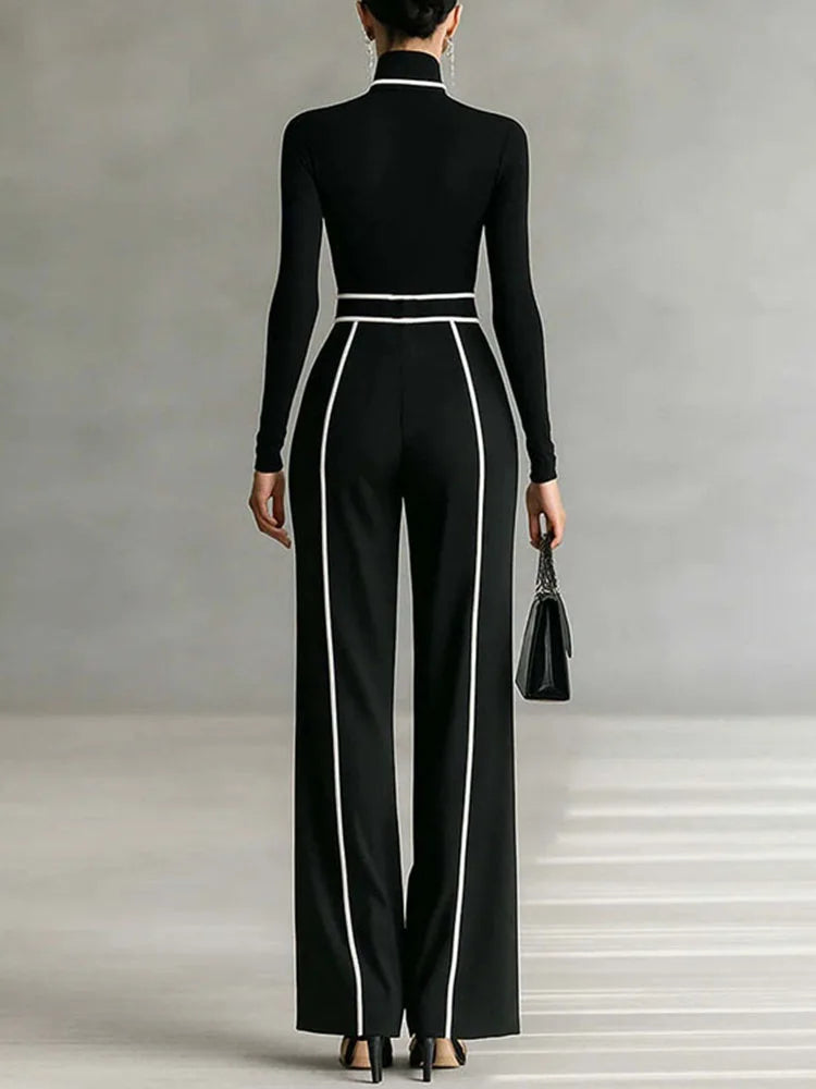 Person wearing a black long-sleeve top and high-waisted pants with white stripes on a neutral background