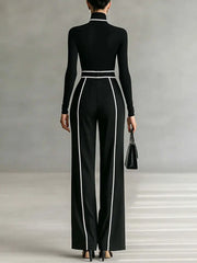 Person wearing a black long-sleeve top and high-waisted pants with white stripes on a neutral background