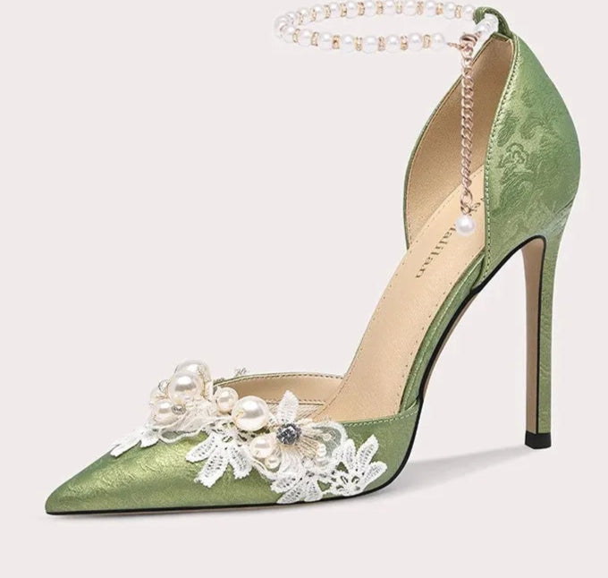 Green high-heeled shoe with floral decorations on a white background