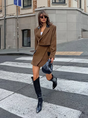 Woman in a brown outfit crossing a zebra crossing with a building in the background