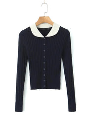 Navy blue sweater with white collar on a hanger against a white background