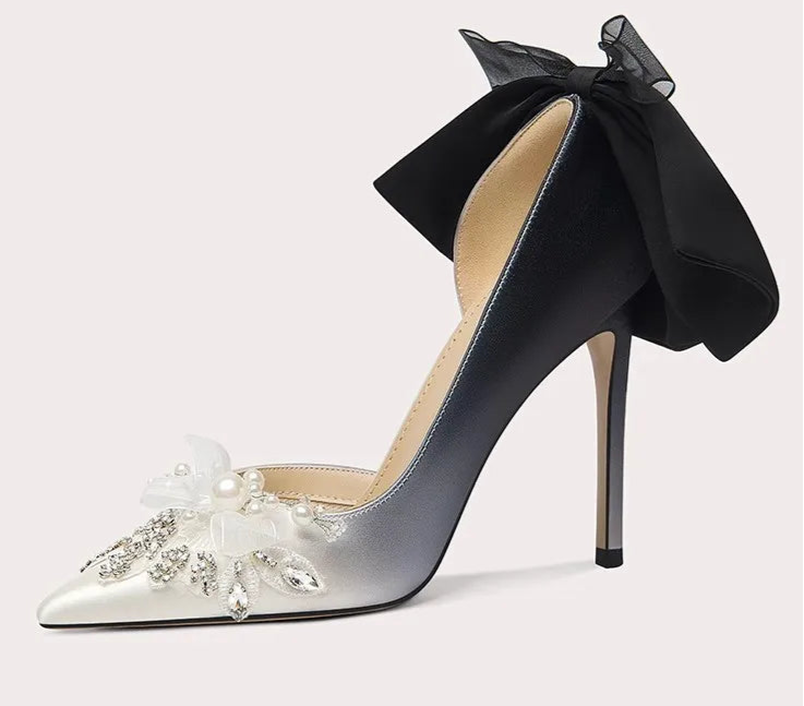 High-heeled shoe with a black bow and floral embellishments on a light gray background