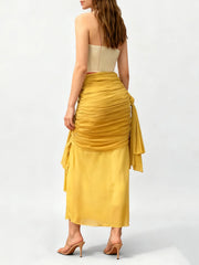 Woman wearing a strapless beige top and yellow ruched skirt on a white background