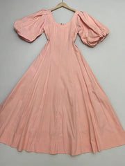 Pink dress with puffed sleeves on a hanger against a gray background