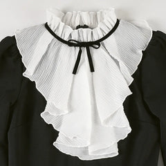 White ruffled collar with black trim on a black background