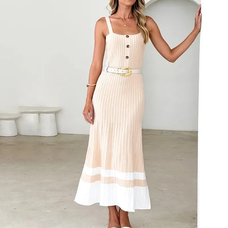 Woman wearing a beige and white dress with a belt in a minimalistic room.