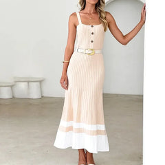 Woman wearing a beige and white dress with a belt in a minimalistic room.