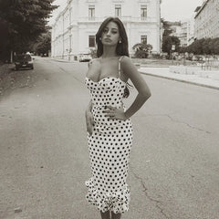 Woman in a polka dot dress standing on a street with buildings in the background