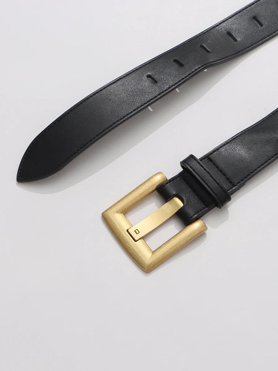 Black leather belt with a gold buckle on a light gray background