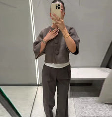 Person wearing a gray outfit taking a mirror selfie in an indoor setting.