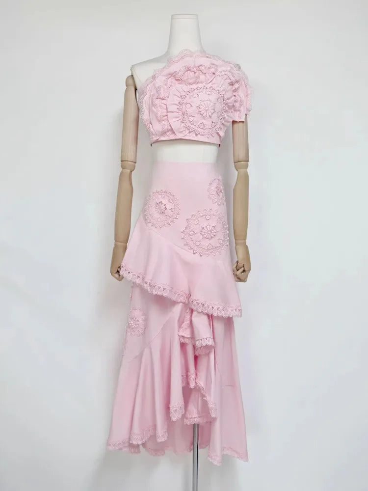 Pink floral lace one-shoulder crop top with an asymmetric ruffle midi skirt on mannequin.