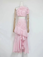 Pink floral lace one-shoulder crop top with an asymmetric ruffle midi skirt on mannequin.