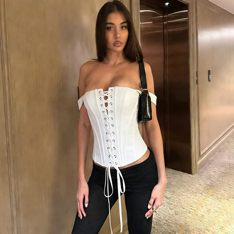 White lace up off shoulder corset top on a woman standing in a hallway.