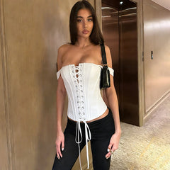 White lace up off shoulder corset top on a woman standing in a hallway.