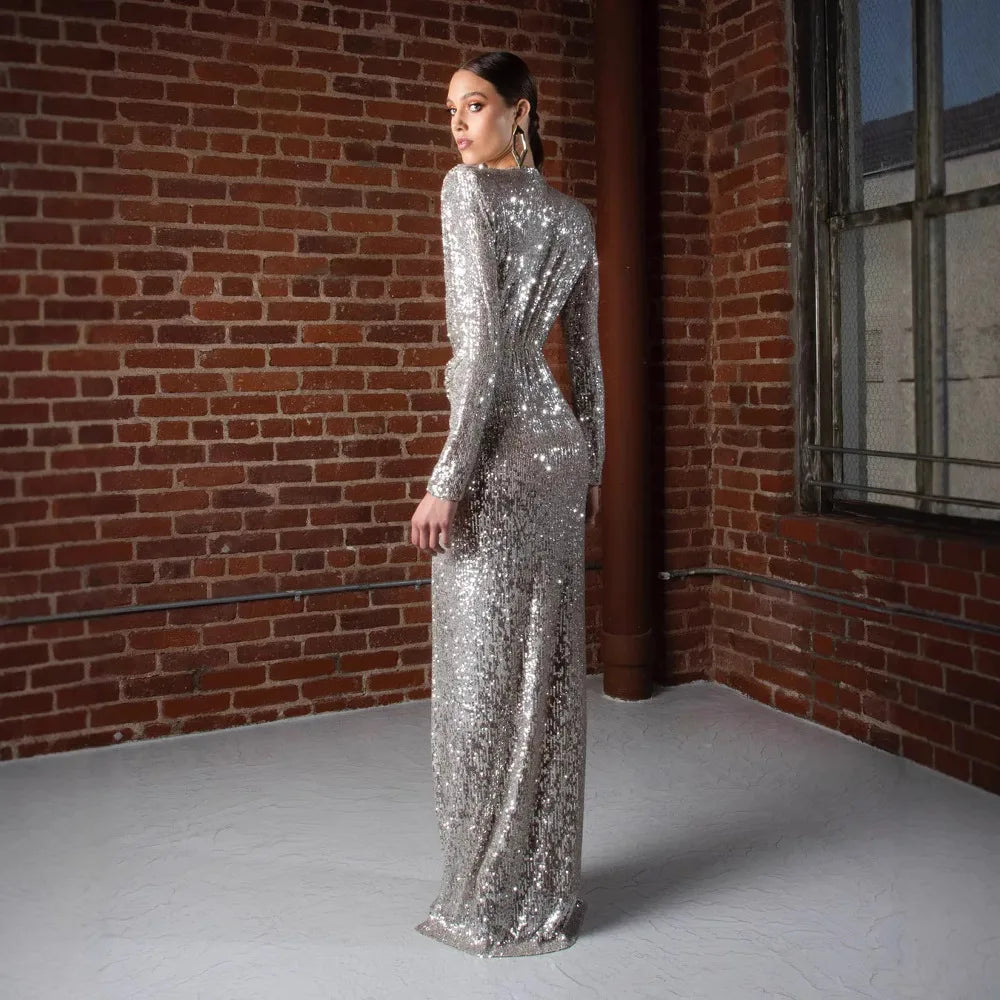 Woman in a silver sequin dress standing against a brick wall.