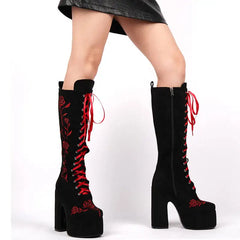 Black knee-high boots with red laces and floral patterns on a white background