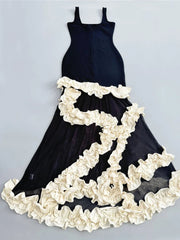 Black dress with white ruffled details on a light gray background