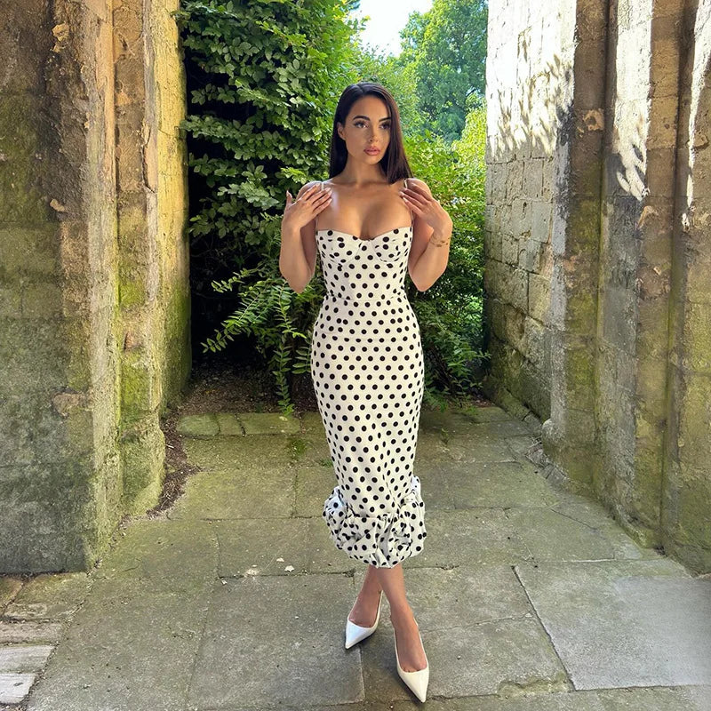 Woman in a polka dot dress standing in a stone pathway with greenery.