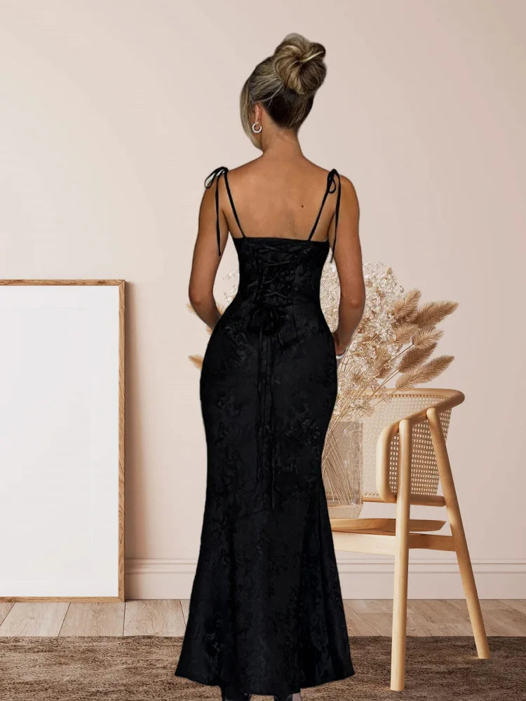 Woman wearing a black dress with thin straps in an indoor setting.