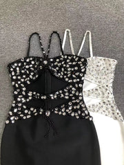 Black strappy top with rhinestone embellishments on a gray background