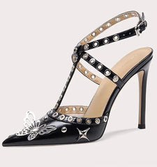 Black high-heeled shoe with decorative straps and embellishments on a white background