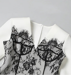 White blouse with black lace details on a gray background