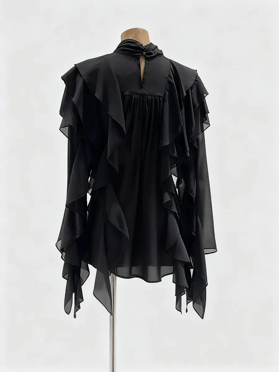Black ruffled blouse on a mannequin against a white background